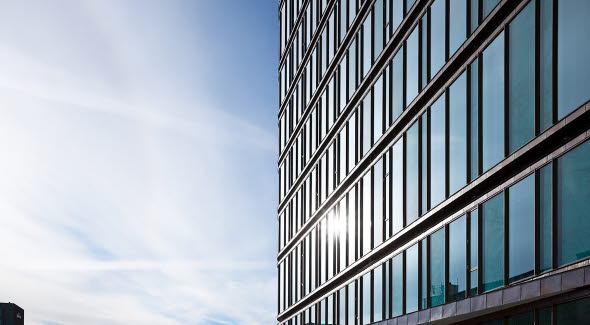 Vinduespartiet på SEB's kontorer i København ses med blå himmel i baggrunden og solens stråler, der rammer vinduerne